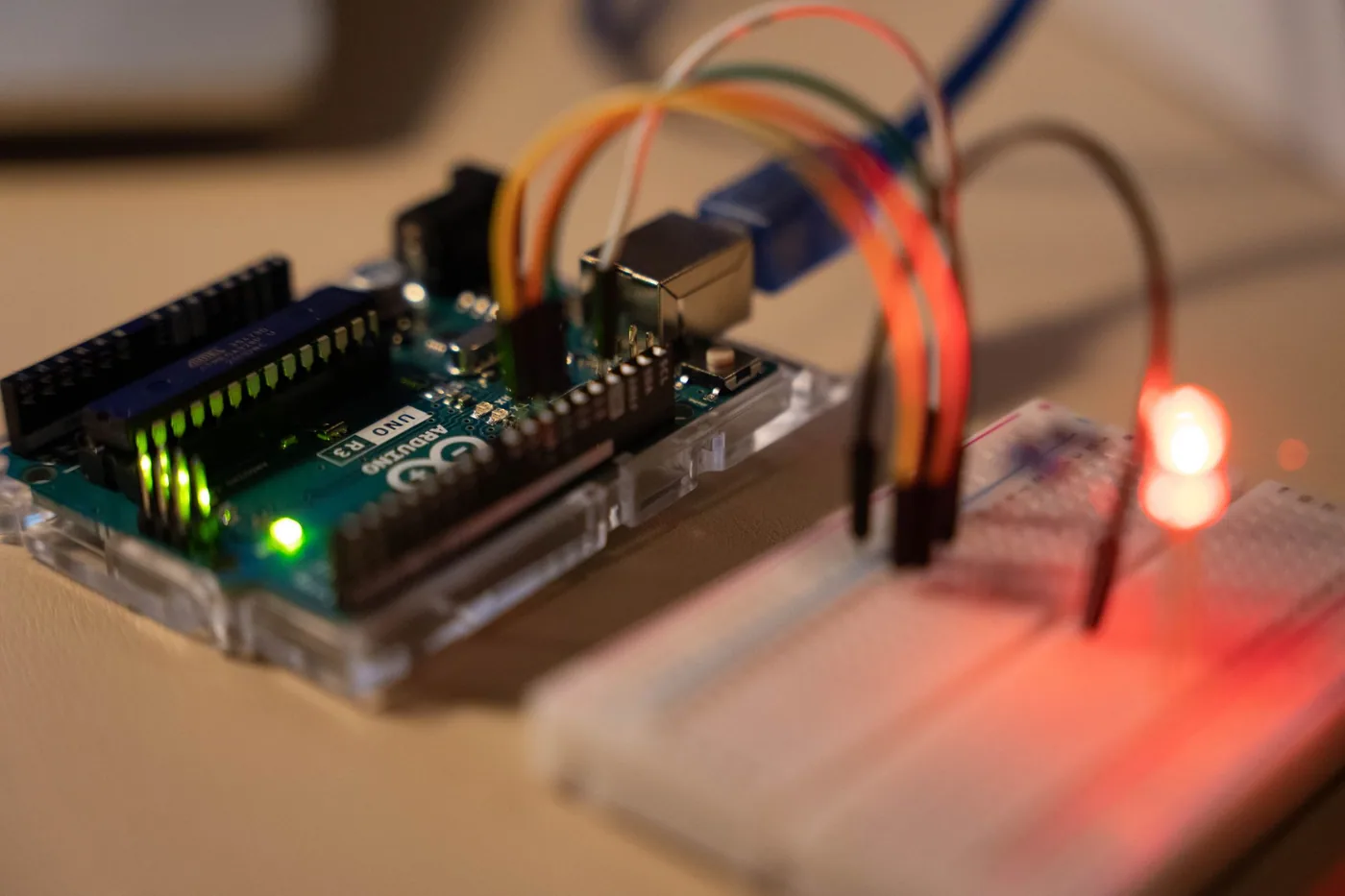 Close-up of a small microcontroller board with jumper wires attached to its header pins.