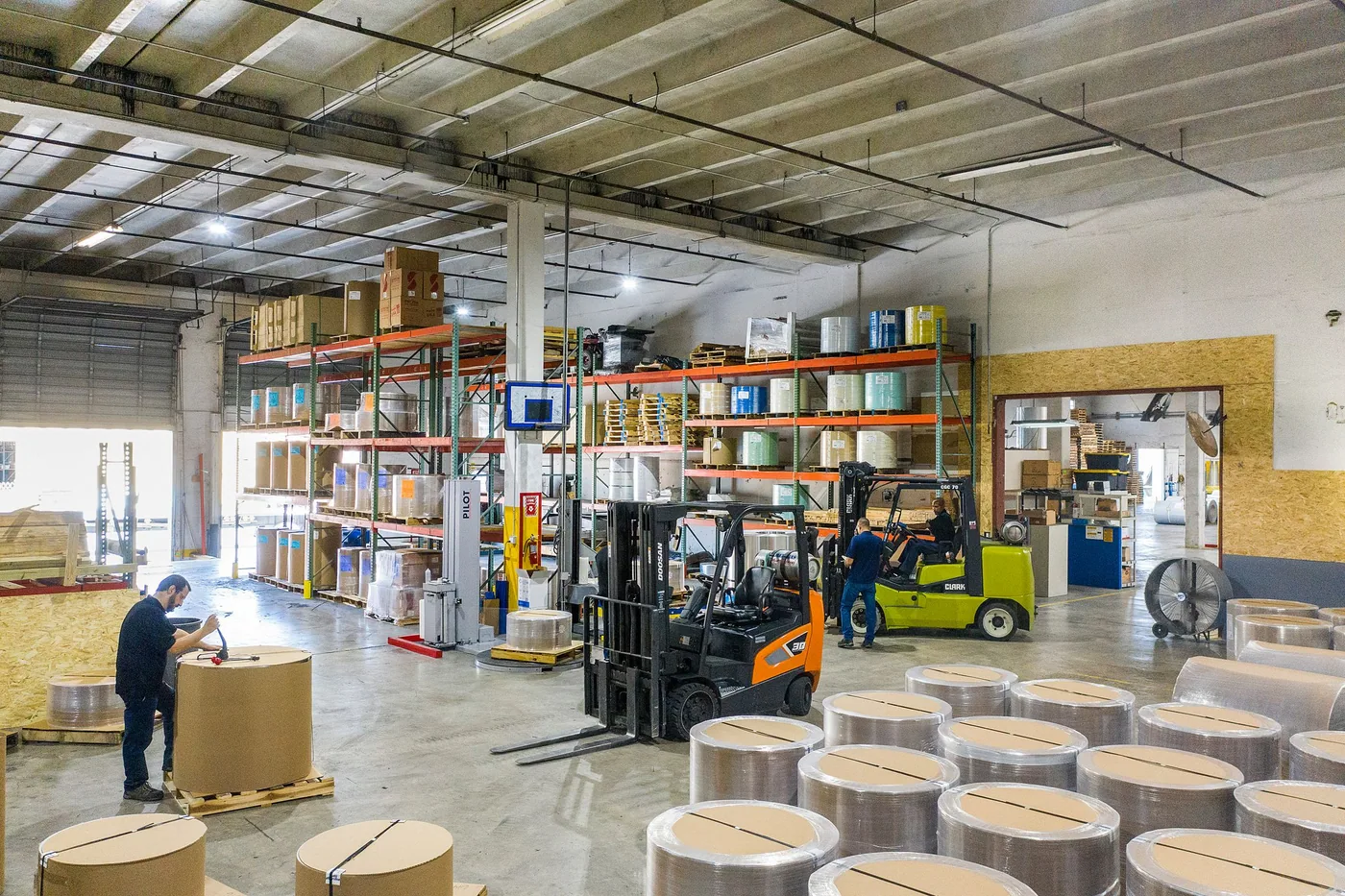 A forklift lifting a loaded pallet beside a warehouse loading dock.