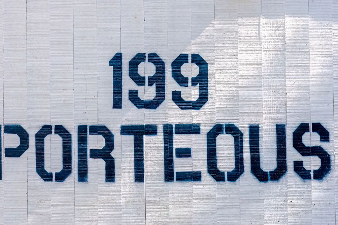 Close-up of a stamped metal rating plate bolted to a piece of electrical equipment.